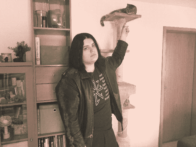 a sepiatone photo of me pointing at my cat on top of a scratching post