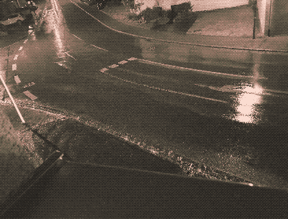 a sepiatone photo of the road outside my window, covered in rain, reflecting streetlights